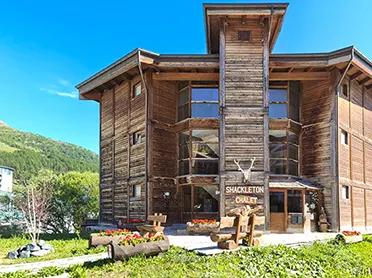 Ingresso principale dello Shackleton Chalet, con architettura alpina in legno e paesaggio naturale.